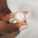 Gold moonstone ring with a moon face design held in a person's hand