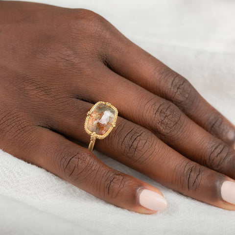 Gold ring with sunstone gemstone on a person's finger