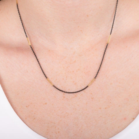 A model wears an oxidized silver and 18k yellow gold chain necklace.