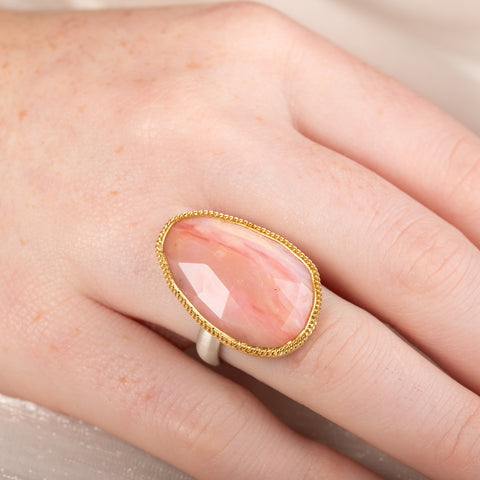 Handcrafted ring with rhodochrosite stone, gold setting and silver band on a hand