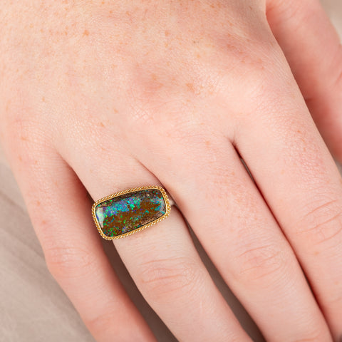 Ring with an opal stone, gold setting and silver band on a hand
