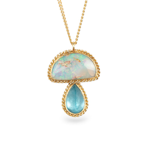 Gold necklace with an mushroom pendant featuring opal and aquamarine stones on a white background