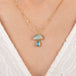 Gold necklace with an mushroom pendant featuring opal and aquamarine stones on a person