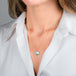 A gold necklace with a teardrop-shaped aquamarine gemstone pendant, shown worn on a model's neck.