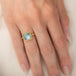 A square-cut light blue aquamarine ring set in an 18k gold bezel, worn on a person's finger.