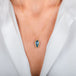 A gold necklace featuring an aquamarine gemstone, shown worn on a model's neck.