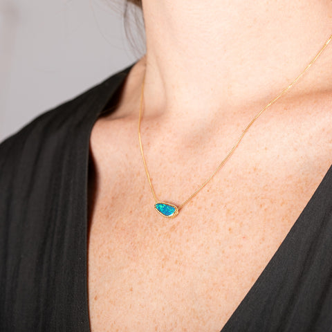 Handmade 18k gold necklace with an opal doublet pendant on a person