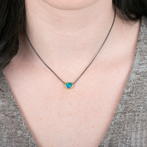 Gold and oxidized silver necklace with an Australian opal doublet on a person