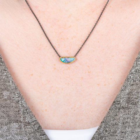Australian opal gemstone necklace with a gold setting and oxidized silver chain on a person