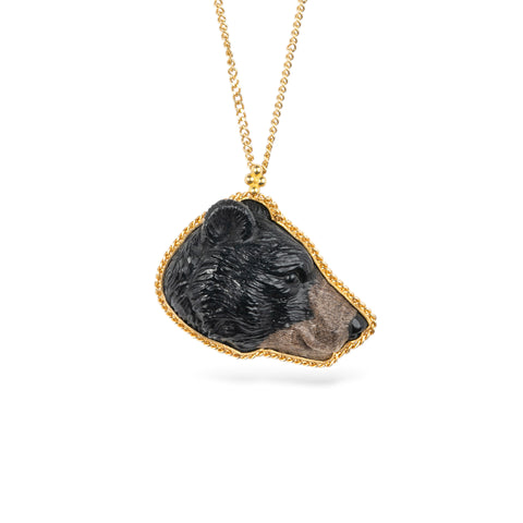 Gold necklace featuring a jasper gemstone carved into a black bear face set against a white background.