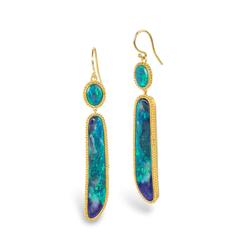 A pair of gold dangle earrings with oval and elongated black opal gemstones, displayed on a clean white background.