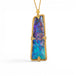 A gold pendant necklace featuring a vertically oriented, rectangular iridescent boulder opal stone with blue and purple play-of-color, set in a textured gold bezel, suspended from a gold chain against a white background.