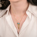 Gold necklace with a boulder opal gemstone pendant draped with a gold tassel on a person