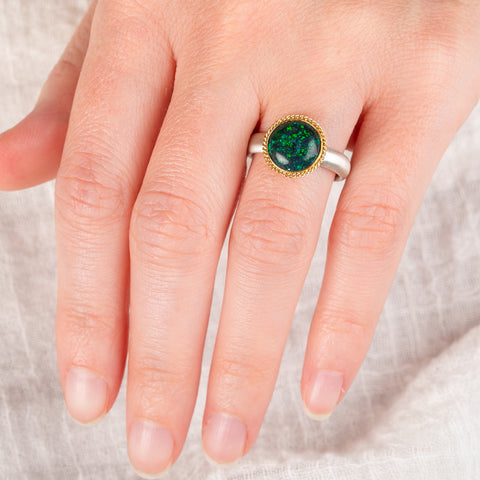 Hand wearing an andamooka opal ring with gold bezel and sterling silver band