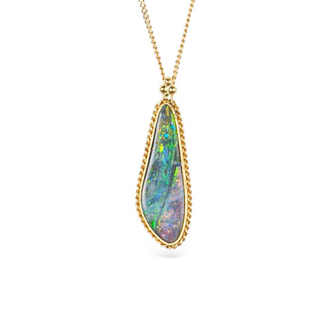 Boulder opal pendant necklace in a gold bezel against a white background