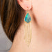 Gold fringe earring with a boulder opal gemstone worn by a person.