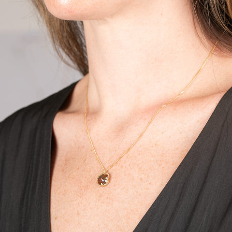 Necklace with a natural brown diamond set in a handmade gold bezel on a person
