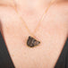 Handcrafted gold necklace with a carved bear made of jasper on a person's neck.