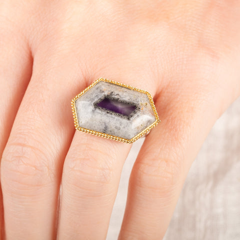 A close up of a person wearing a handmade fine jewelry amethyst gemstone ring set in 18k gold with a sterling silver band
