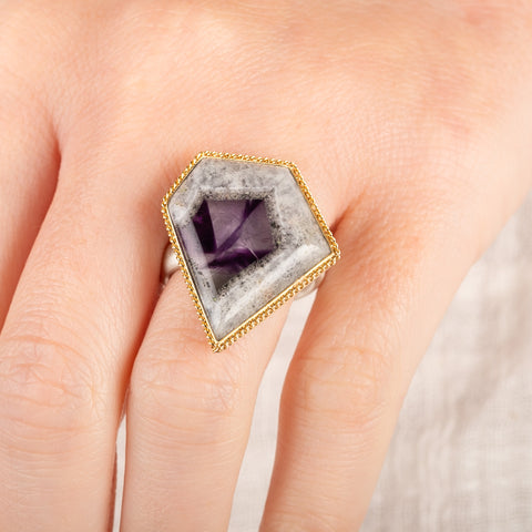 Close up of a person wearing a handmade fine jewelry amethyst gemstone ring set in 18k gold with a sterling silver band