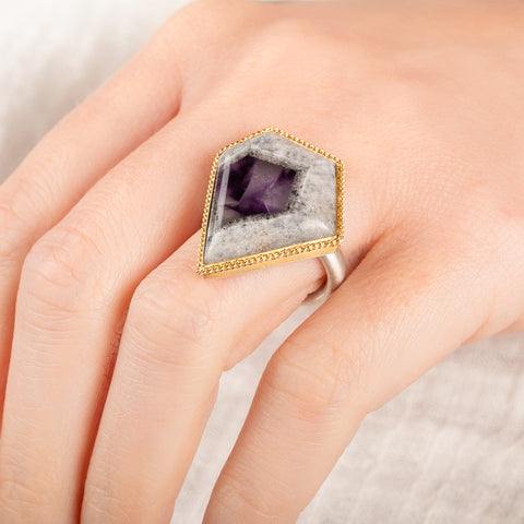 Close up of a person wearing a handmade fine jewelry amethyst gemstone ring set in 18k gold with a sterling silver band