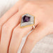 Close up of a person wearing a handmade fine jewelry amethyst gemstone ring set in 18k gold with a sterling silver band