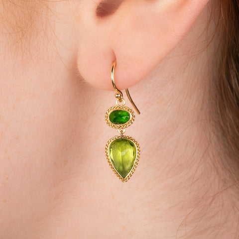 Gold earring featuring chrome diopside and peridot gemstones, shown worn in a person's ear.
