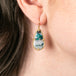 Teardrop-shaped earring with a chrysocolla stone worn by a person.