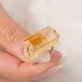A gold ring featuring a large, rectangular, Citrine gemstone set in a detailed gold bezel, held in hand.