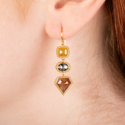 Gold earring featuring trio of colorful diamonds, shown worn in a person's ear.