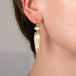 A model wears a handmade 18k gold earring featuring crystal quartz and rutilated quartz gemstones.