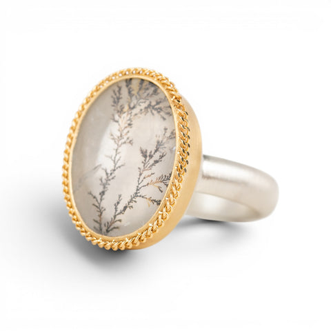 Gold and silver ring featuring a dendritic quartz stone on a white background