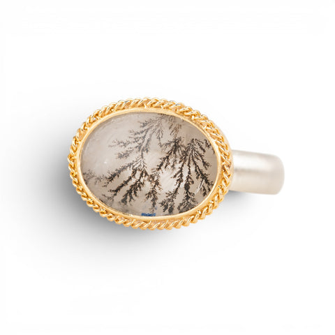 Gold and silver ring with a dendritic quartz stone on a white background