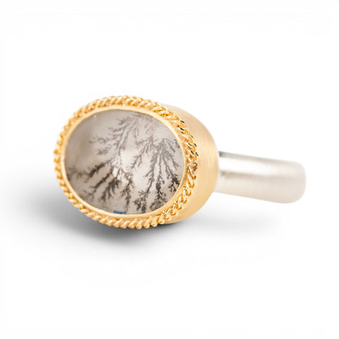 Gold and silver ring with a dendritic quartz stone on a white background