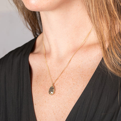 Necklace with a teardrop-shaped diamond set in a handcrafted gold bezel on a person