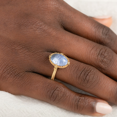 Gold ring with a blue dumortierite stone on person's finger