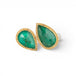 A gold and silver ring featuring two emerald stones against a white background