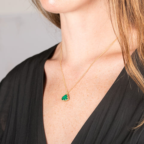 Handcrafted 18k gold necklace with an emerald pendant worn by a person.