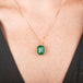 Handcrafted gold necklace with an emerald gemstone pendant on a model's neck.