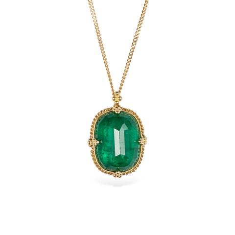 Handcrafted gold necklace with an emerald gemstone pendant on a white background.