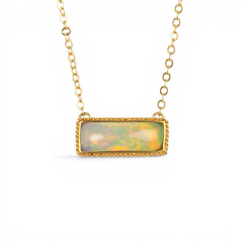 A gold necklace featuring an ethiopian opan necklace against a white backround