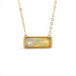 A gold necklace featuring an ethiopian opan necklace against a white backround