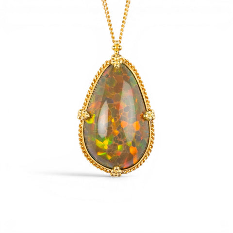 A teardrop-shaped Ethiopian Opal necklace set in a gold bezel against a white background
