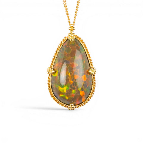 A teardrop-shaped Ethiopian Opal necklace set in a gold bezel against a white background