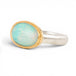 An oval ring featuring a light blue-green opal stone in a gold setting, with a silver-toned band, shown on a plain white background.