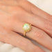 Gold ring featuring a circular Ethiopian opal gemstone set in a handmade 18k gold bezel, worn on a person's finger.