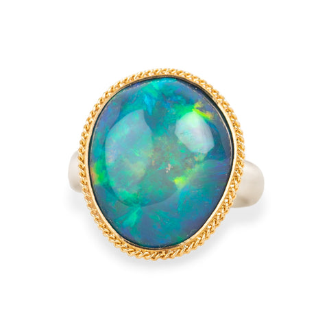 Ring with a large opal stone set in a gold bezel with a silver band on a white background