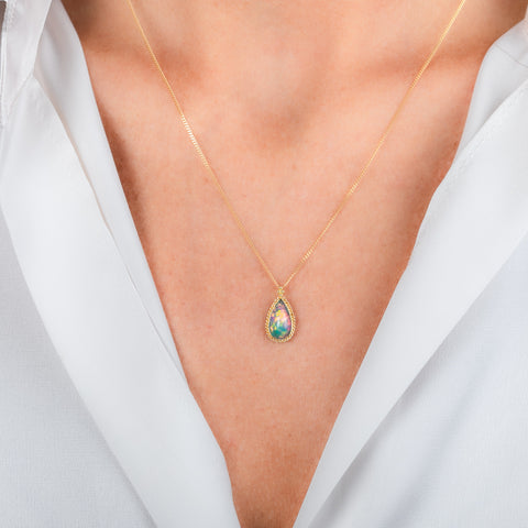 A gold teardrop-shaped Ethiopian Opal necklace worn on a person's neck.