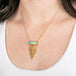 A necklace featuring an ethiopian opal draped with a gold tassel on a person