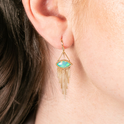 Gold earring with ethiopian opal stone worn by a person